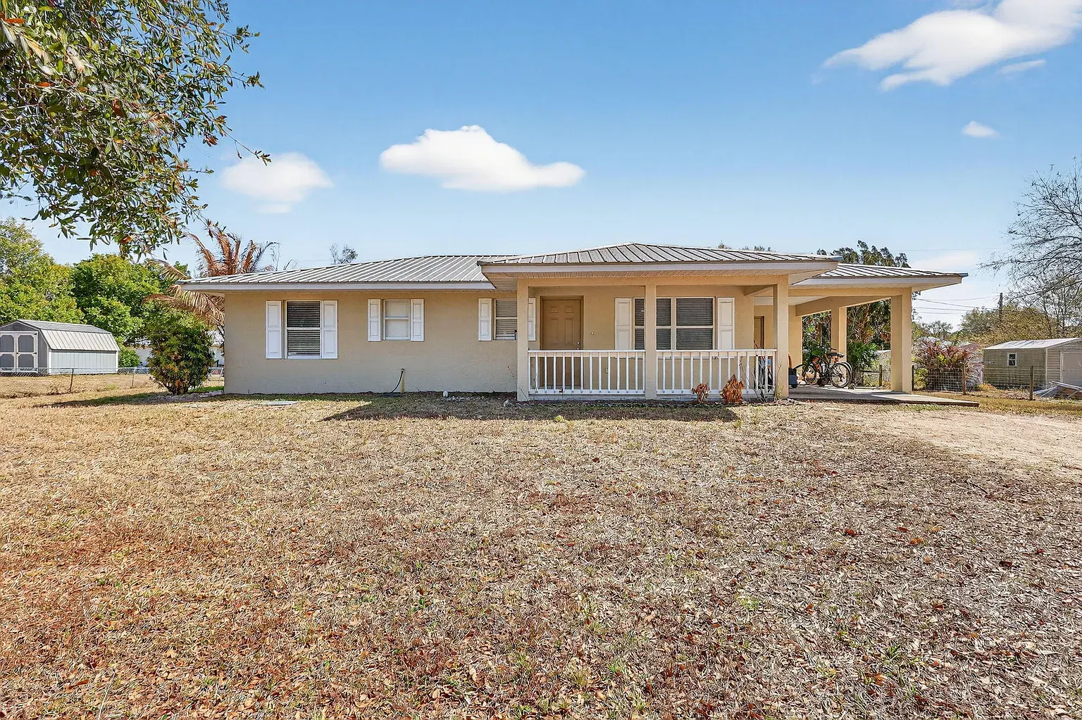 Front of the Okeechobee home, with a covered porch, standing-seam metal roof and attached carport